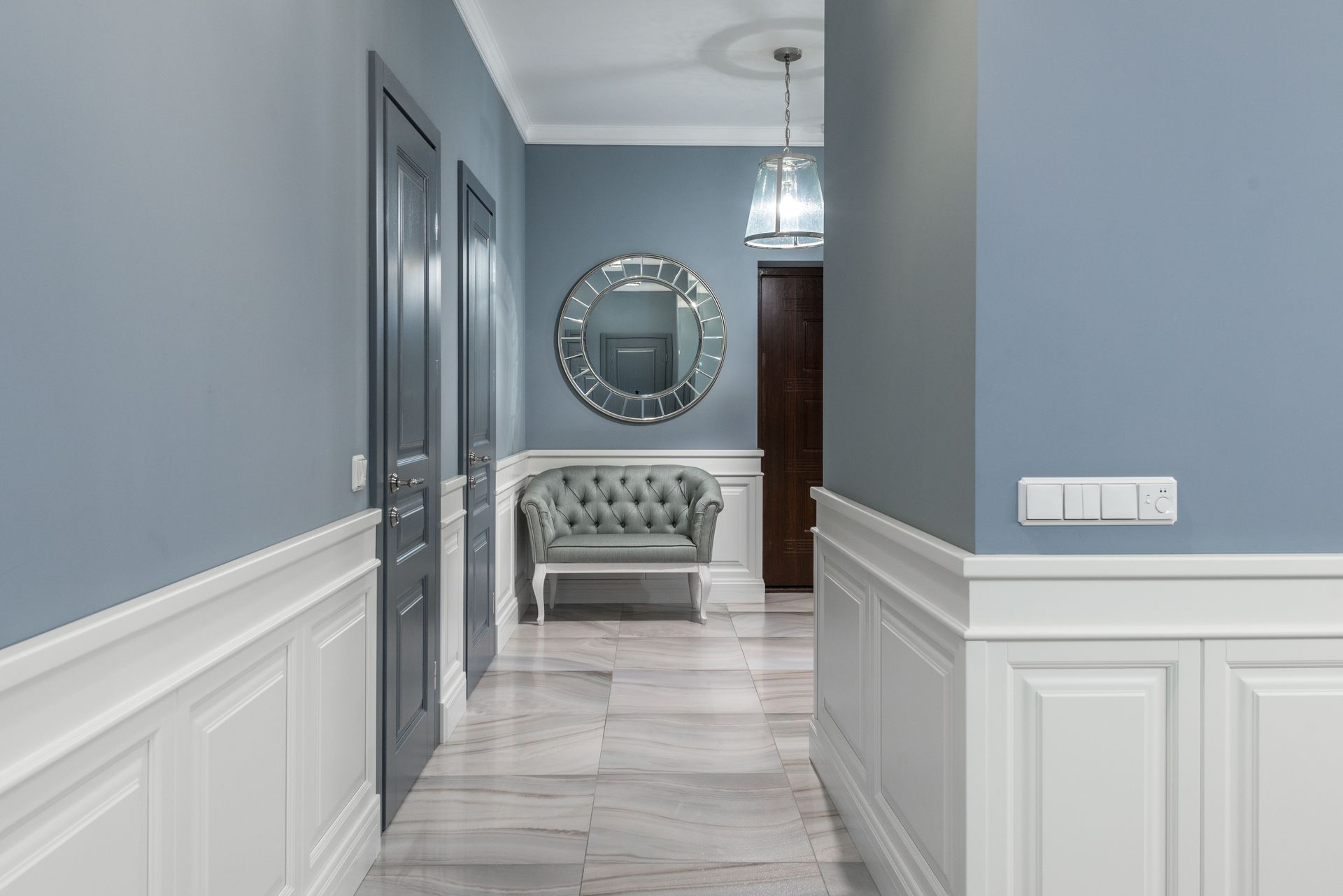 Stylish interior corridor featuring an elegant armchair, decorative mirror, and soft lighting.